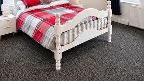 Une chambre à coucher avec un lit, une table de chevet, une lampe et un tableau au mur.