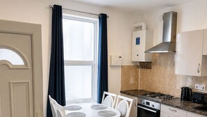 Une cuisine compacte comprenant un coin repas, une cuisinière, un grille-pain et une machine à café.