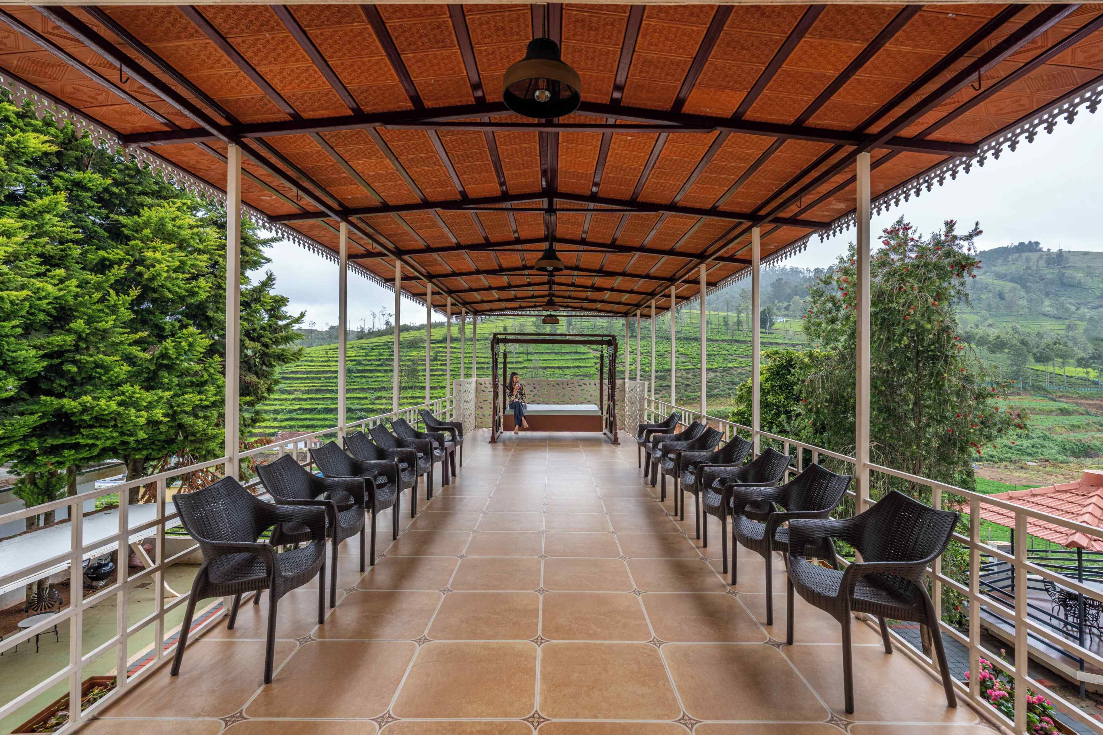 A covered terrace with chairs facing a scenic view of terraced fields and hills.