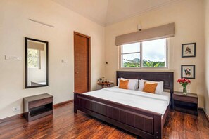 Ein Schlafzimmer mit einem großen Bett, einer Holztür, einem Fenster mit Aussicht, einem Nachttisch und einem Spiegel.