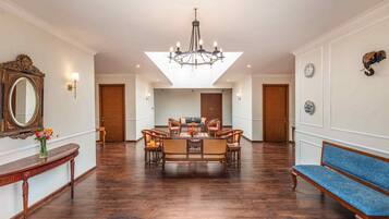 A spacious room with a chandelier, a dining table with chairs, a bench, and a large mirror on the wall.