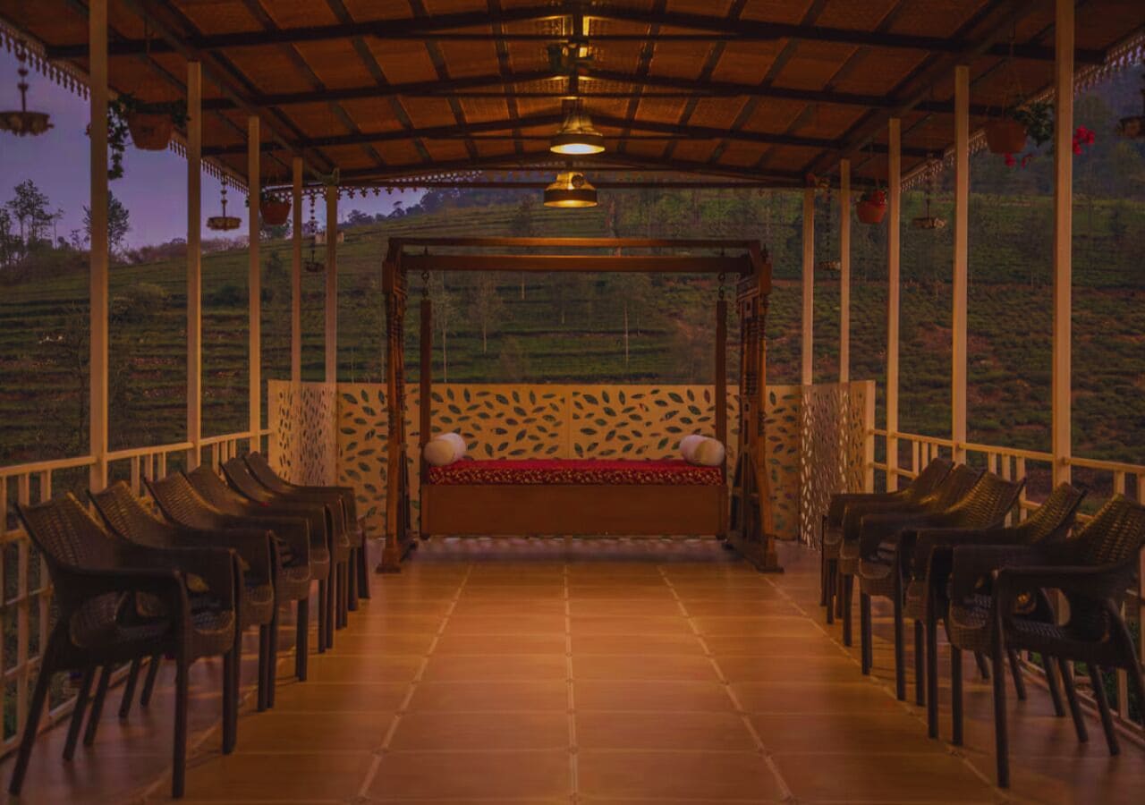 A covered outdoor seating area with a bench and chairs, surrounded by a wooden fence and a patterned wall.
