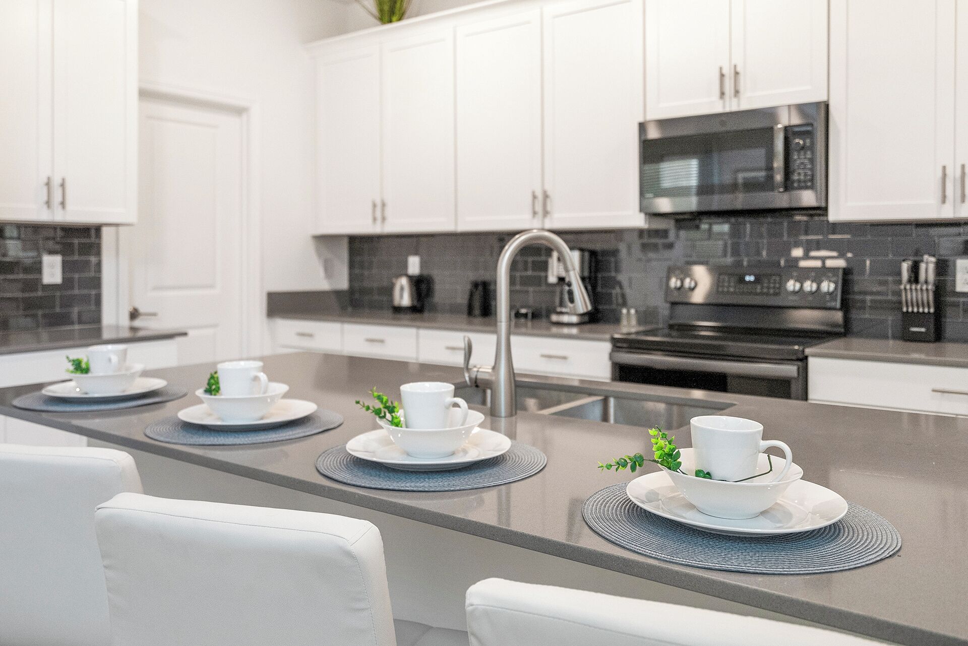 A modern kitchen with white cabinets, a stainless steel island, and a built-in microwave.