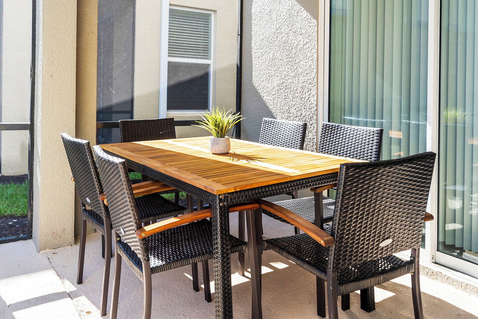 A wooden table with six chairs, a potted plant, and a window with blinds.