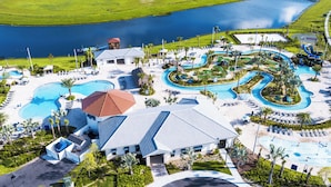 A resort with multiple swimming pools, a large central building, and a view of a lake.