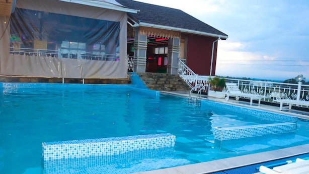 Una piscina con borde de azulejos, zona techada con escalones y barandilla blanca.