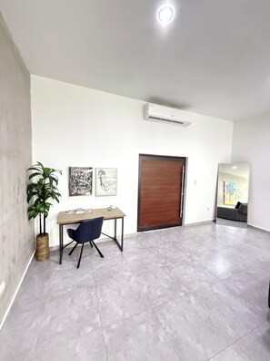 Ein modernes Interieur mit Schreibtisch, Stuhl, Topfpflanze, Kunstwerk und Klimaanlage.