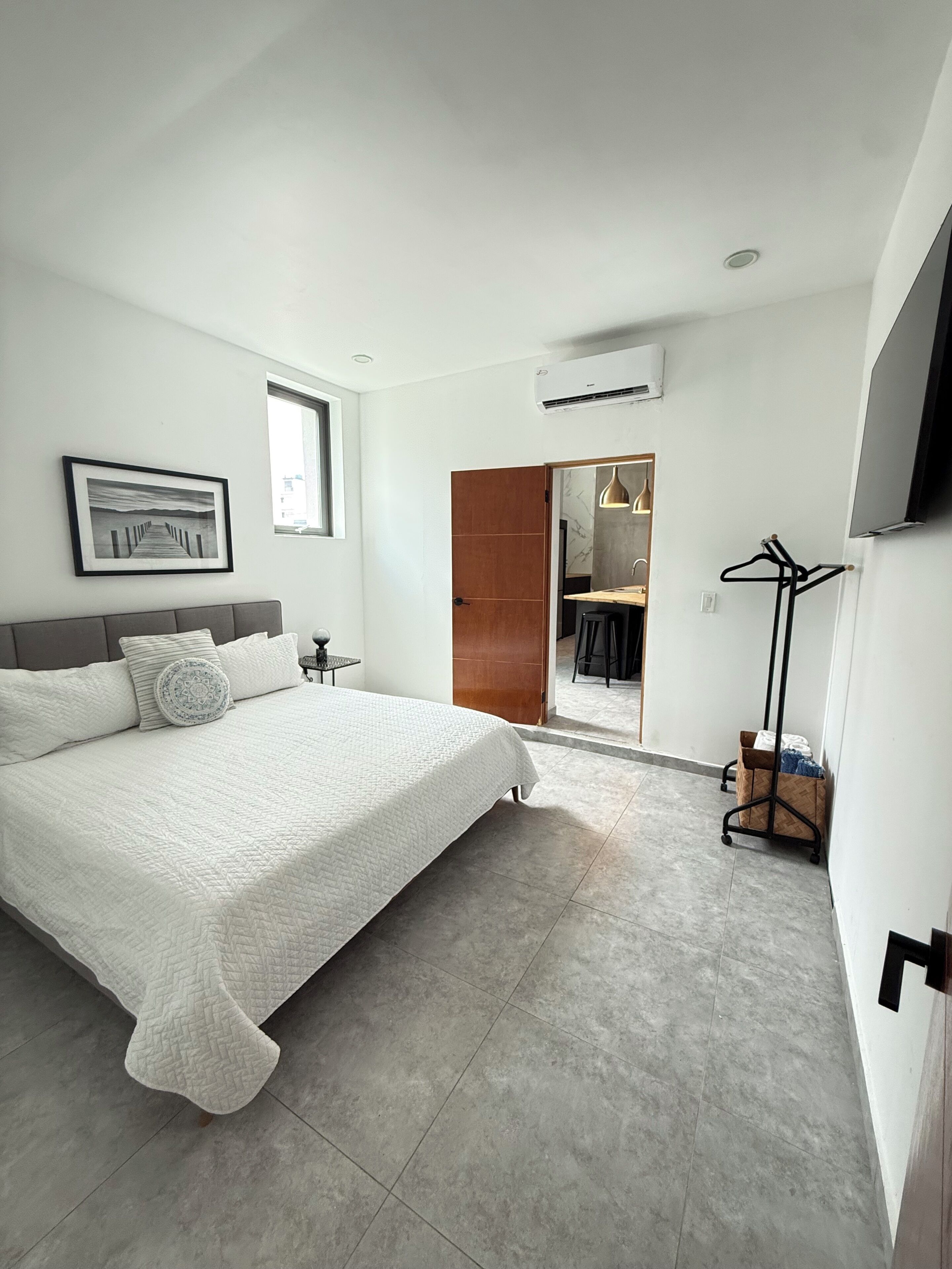 Une chambre à coucher moderne avec un grand lit, un tableau encadré au mur et un dressing doté d’un miroir.