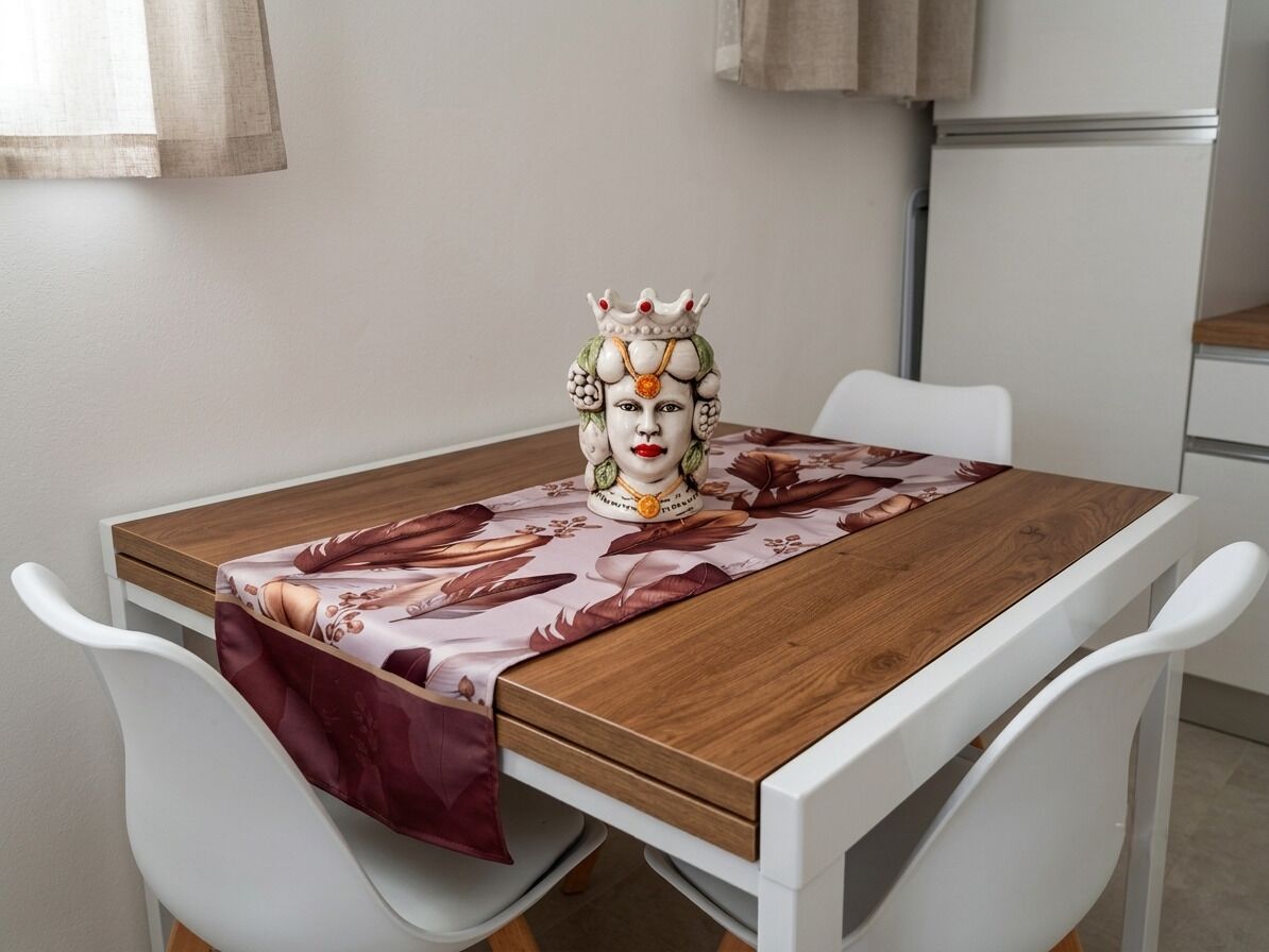 Een eettafel met een tafelkleed met bloemenprint, witte stoelen en een decoratief object op de tafel.