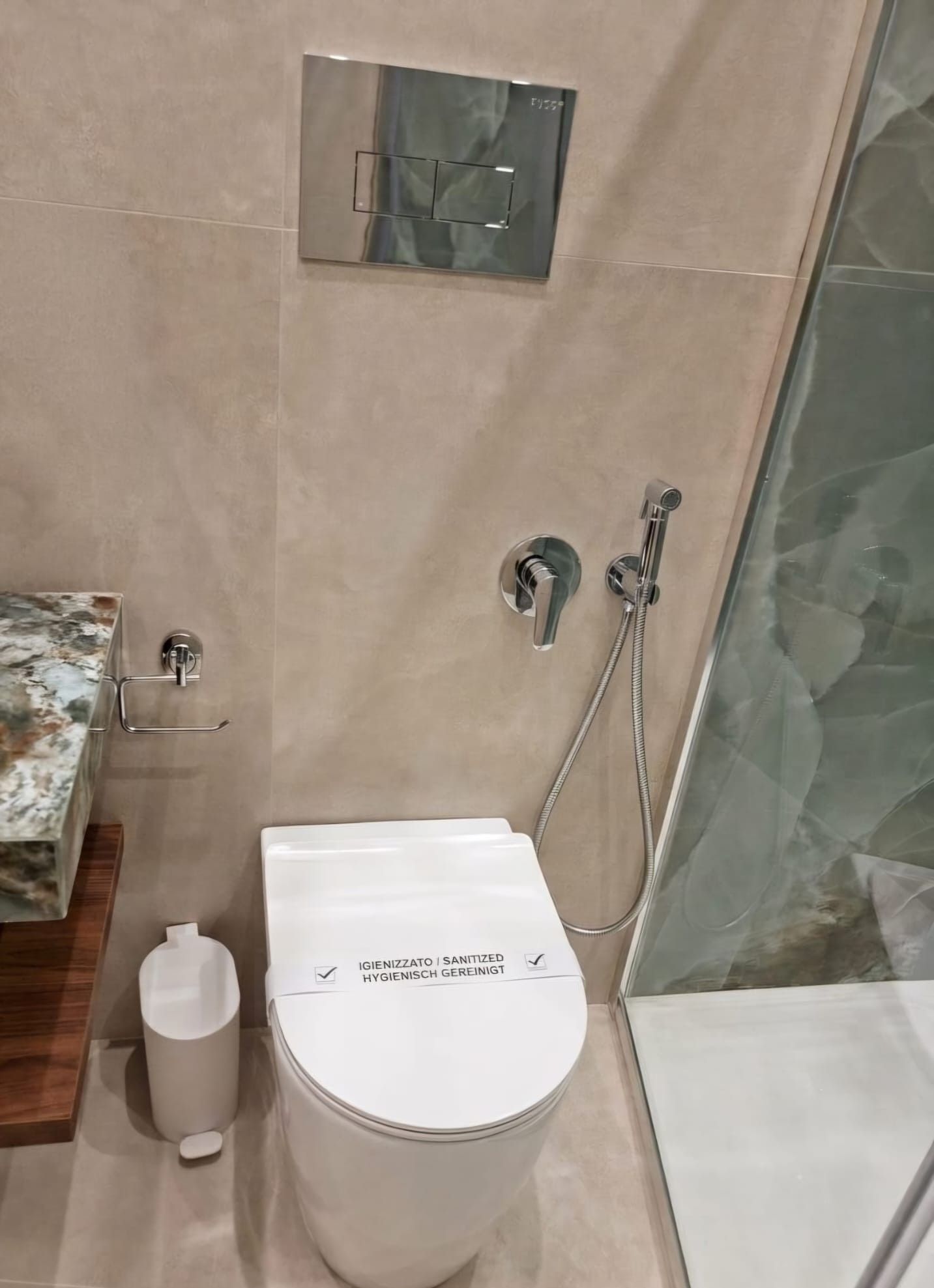 Een badkamer met een toilet, een douche en een marmeren aanrechtblad.