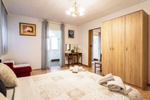 A bedroom with a bed, a desk, a wardrobe, and a bathroom visible through an open door. - A1 - Cozy apartment with pool and spacious terrace, 2 min walk to beach (Omiš)