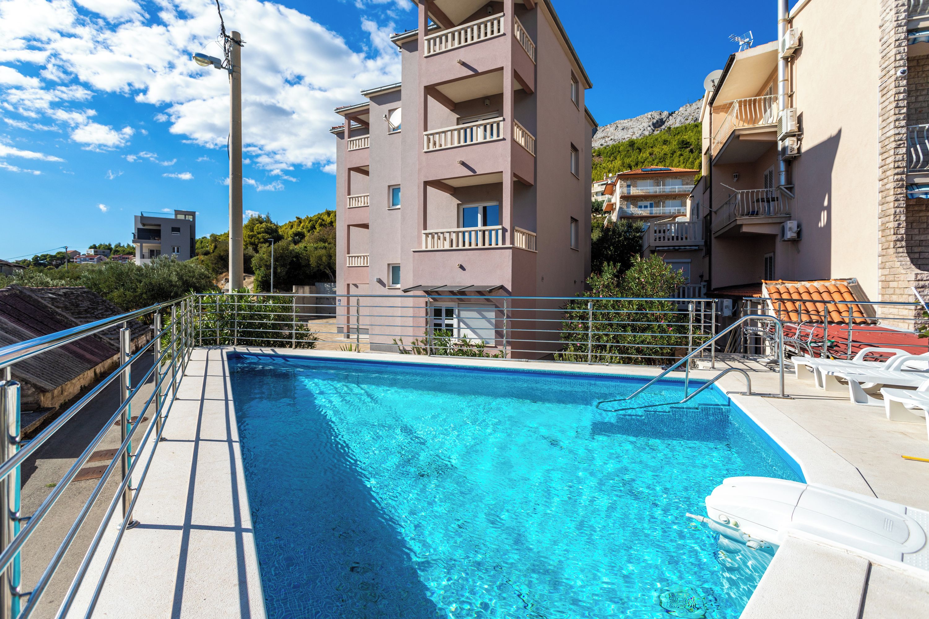 A swimming pool with a metal railing, surrounded by buildings with balconies.