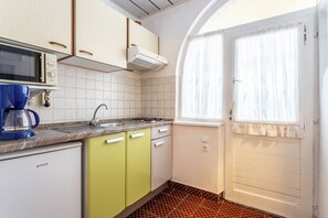 A compact kitchen with a microwave, coffee maker, sink, and a window with curtains. - A1 - Cozy apartment with pool and spacious terrace, 2 min walk to beach (Omiš)