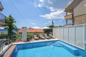 A swimming pool with lounge chairs and a view of a building with a red-tiled roof. - A1 - Cozy apartment with pool and spacious terrace, 2 min walk to beach (Omiš)