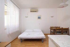 A bedroom with a bed, a dining table, chairs, an air conditioner, and a picture on the wall. - A1 - Cozy apartment with pool and spacious terrace, 2 min walk to beach (Omiš)