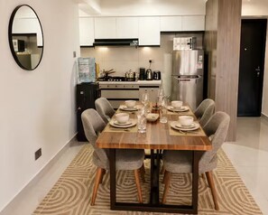 A modern dining area with a wooden table set for six, surrounded by grey upholstered chairs. - "Beautiful luxurious spacious 2 bedroom 
apartment with amazing amenities..." (Nairobi)
