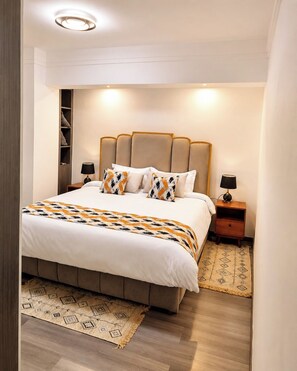 A bedroom with a bed, nightstands, a headboard, and a wall-mounted shelf. - "Beautiful luxurious spacious 2 bedroom 
apartment with amazing amenities..." (Nairobi)