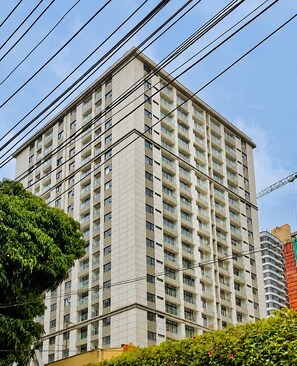 A multi-story building with a grid of windows and balconies, surrounded by greenery and power lines. - "Beautiful luxurious spacious 2 bedroom 
apartment with amazing amenities..." (Nairobi)