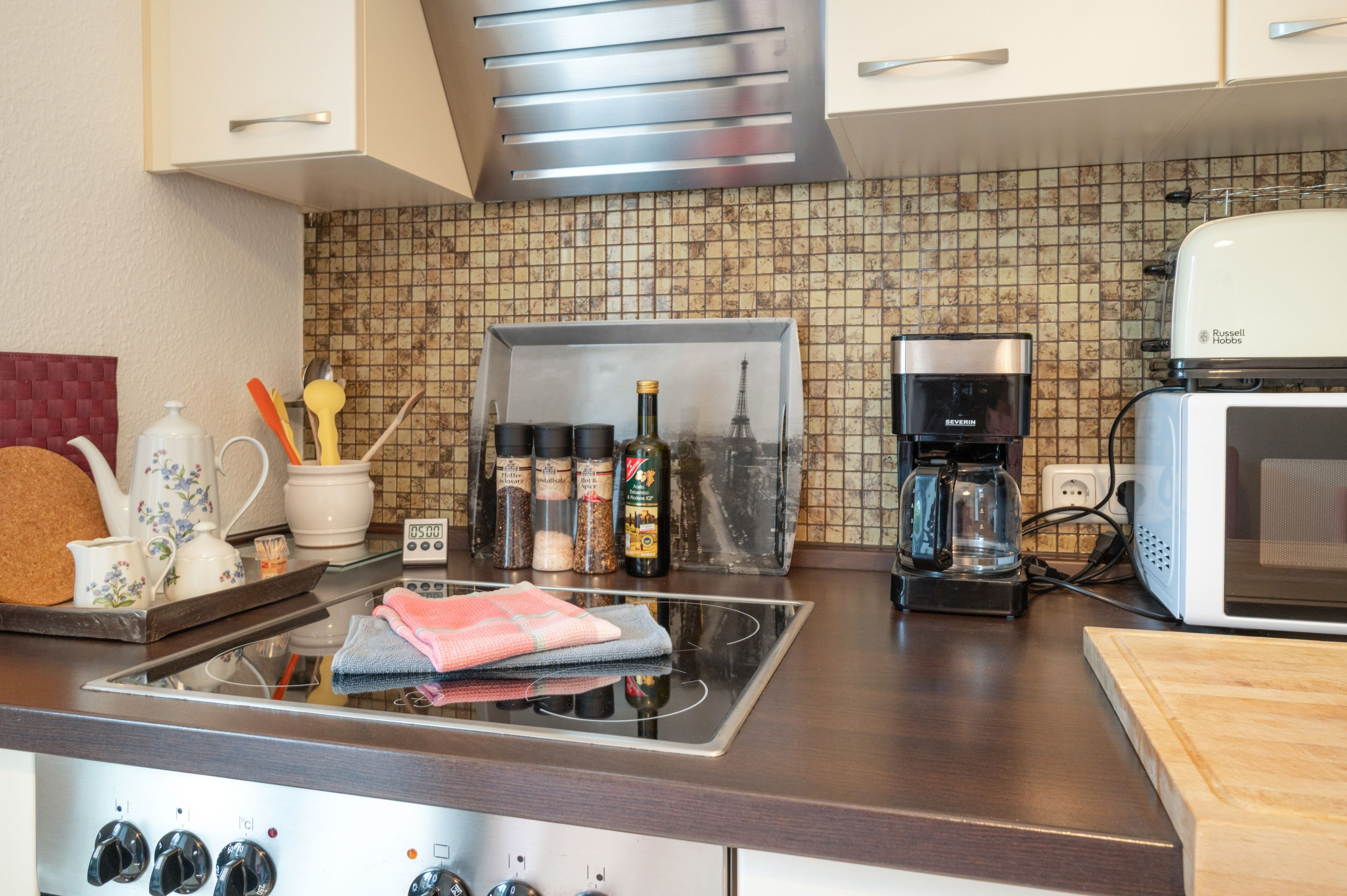 Una cocina con microondas, cafetera y varios utensilios de cocina sobre la encimera.
