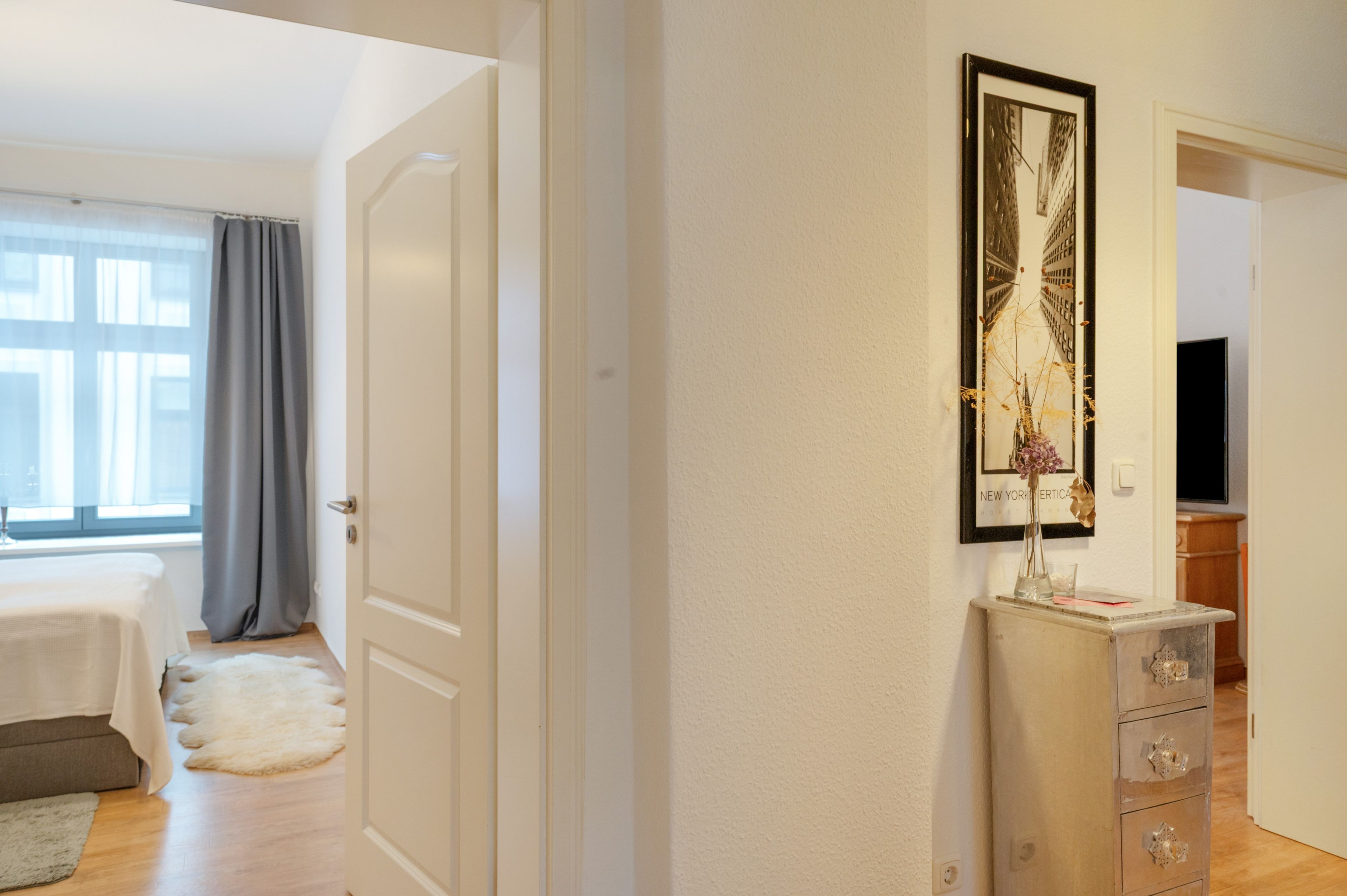 A hotel room with a bed, a dresser, a mirror, and a window with curtains.