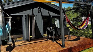 Um deck de madeira com uma rede, uma mesa e cadeiras.