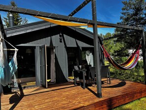 A wooden deck with a hammock, a table, and chairs.