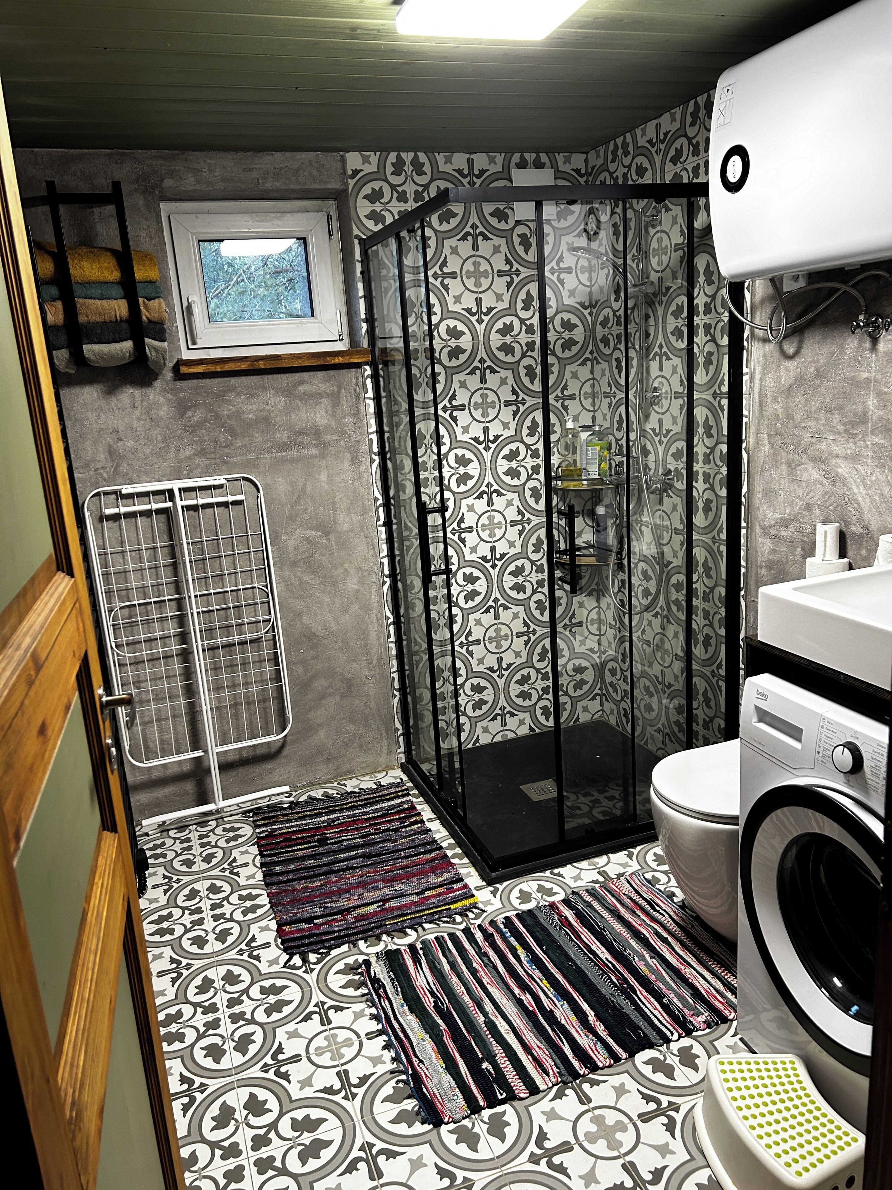 Une salle de bain compacte comprenant une douche, des toilettes et un lave-linge.