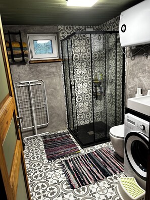 A compact bathroom with a shower, toilet, and washing machine.