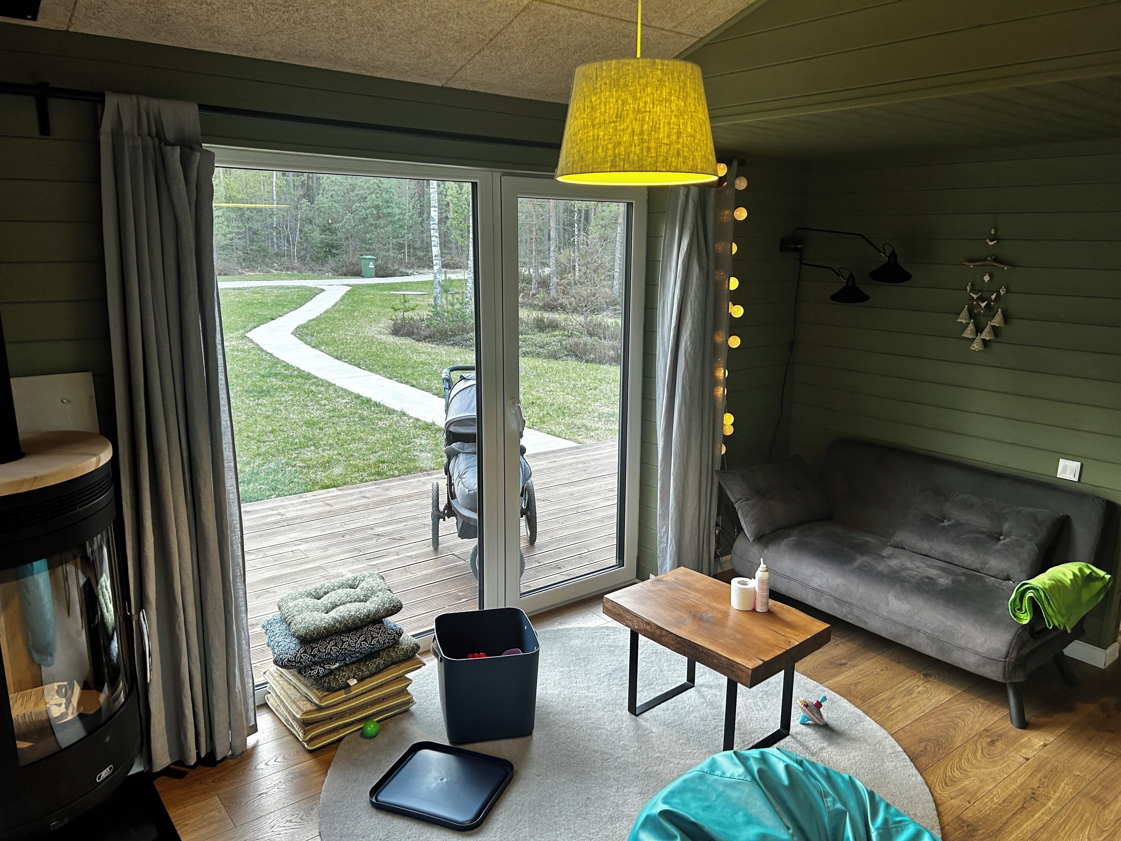 Uma sala de estar acolhedora com sofá, mesa de centro, televisão e vista para um jardim através de uma porta de vidro deslizante.