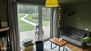 Uma sala de estar acolhedora com sofá, mesa de centro, televisão e vista para um jardim através de uma porta de vidro deslizante.