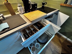 Una cocina con estufa integrada, cafetera y tabla de cortar.