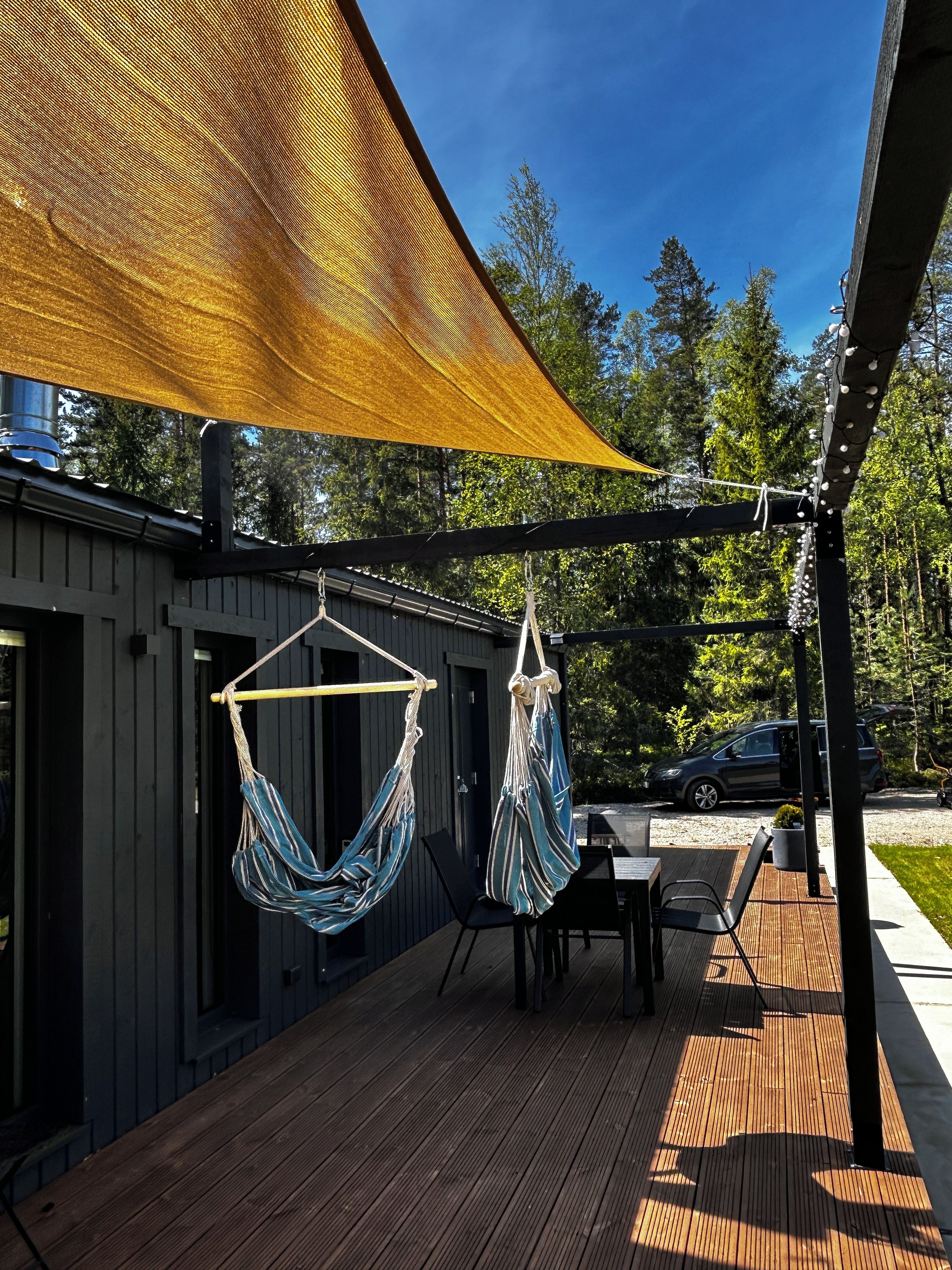A wooden deck with two hammocks, a table, and chairs.