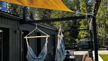 A wooden deck with two hammocks, a table, and chairs.