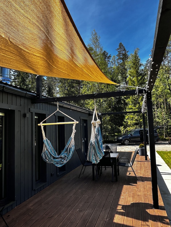 A wooden deck with two hammocks, a table, and chairs.