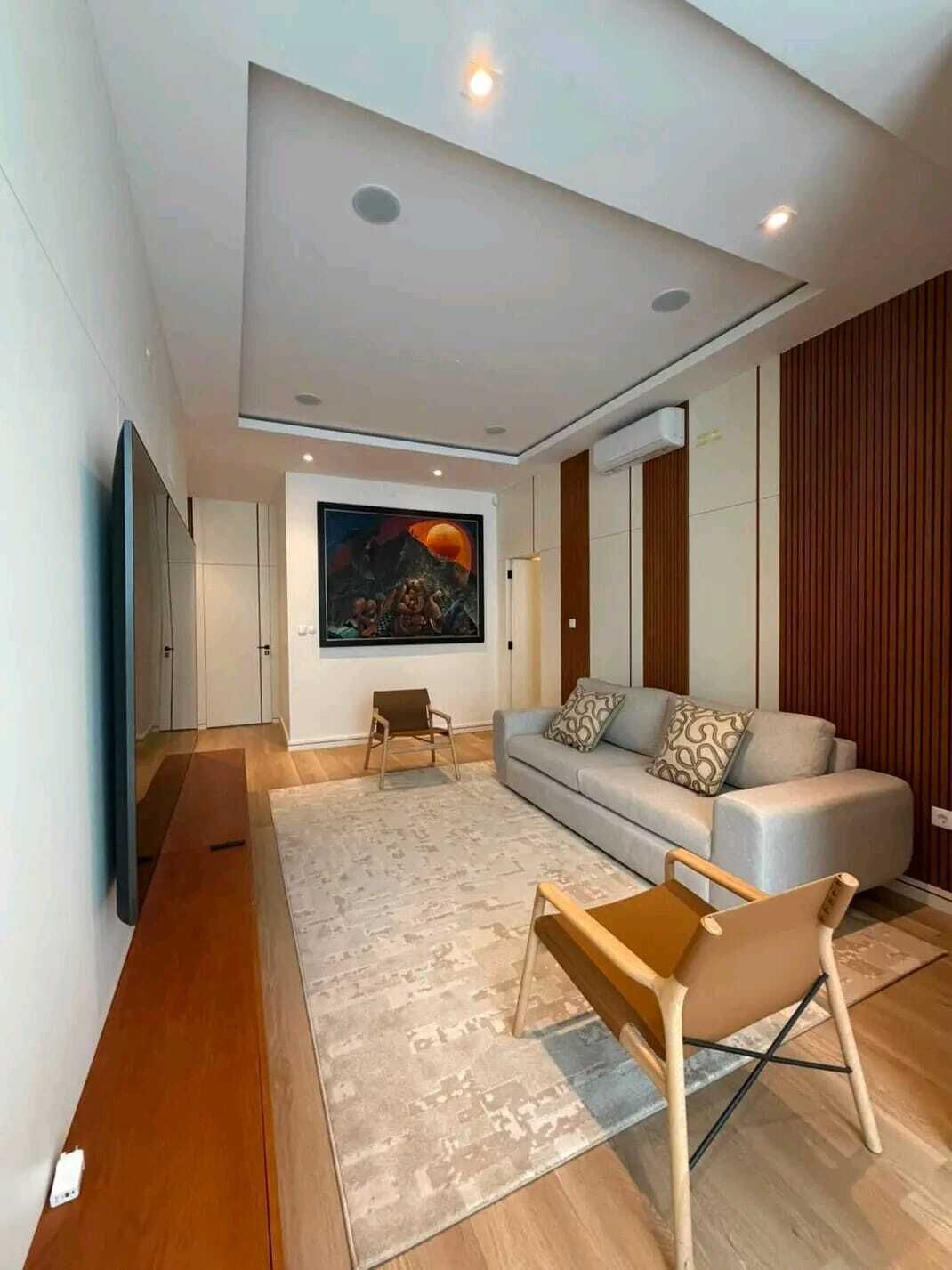 Uma sala de estar moderna com um sofá, uma mesa de centro e uma televisão.