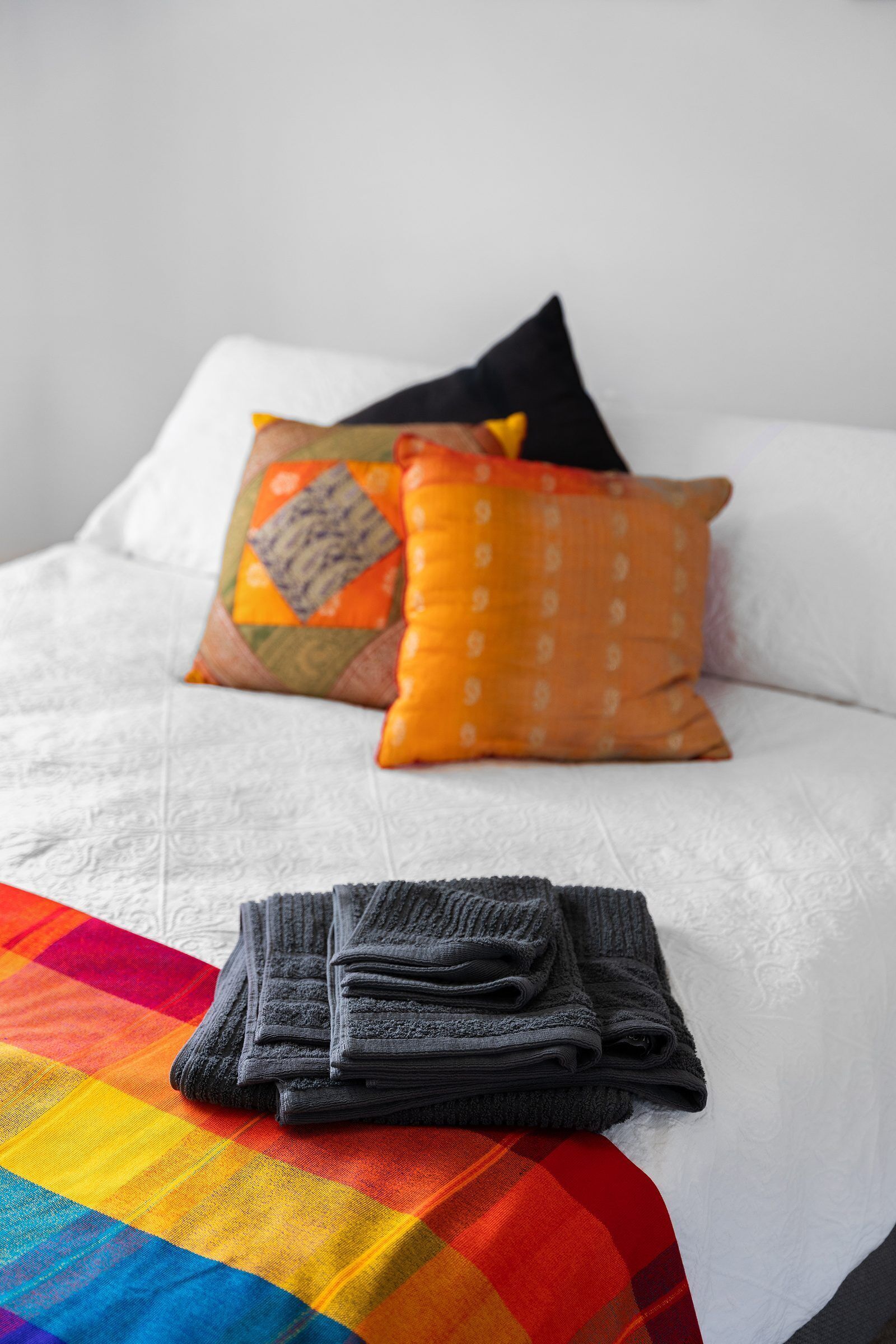 A neatly made bed with a white sheet, two pillows, and a folded towel.