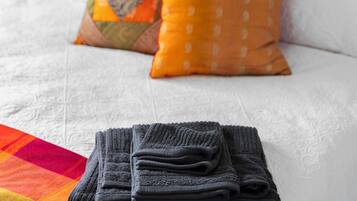 A neatly made bed with a white sheet, two pillows, and a folded towel.
