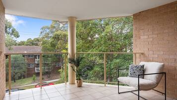 A balcony with a chair, a potted plant, and a view of a residential area.