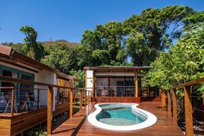 A wooden deck with a swimming pool, surrounded by trees and a building with a balcony. - POUSADA VEREDAS NORONHA (Fernando de Noronha)