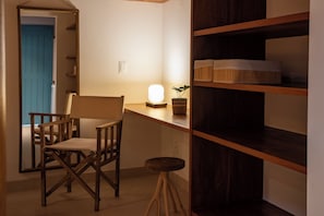 A room with a desk, chair, shelves, and a plant. - POUSADA VEREDAS NORONHA (Fernando de Noronha)