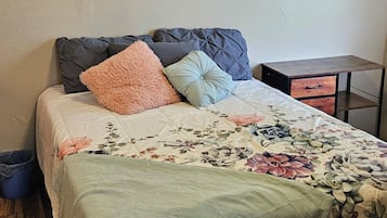 A bedroom with a bed, a nightstand, a dresser, and two wall-mounted paintings.