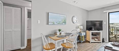 A modern living room with a dining area, a flat-screen TV, and a view of the city.