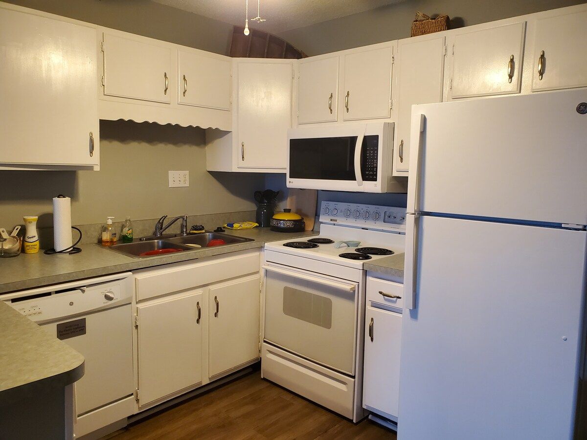 A kitchen with white cabinets, a microwave, a stove, and a refrigerator.