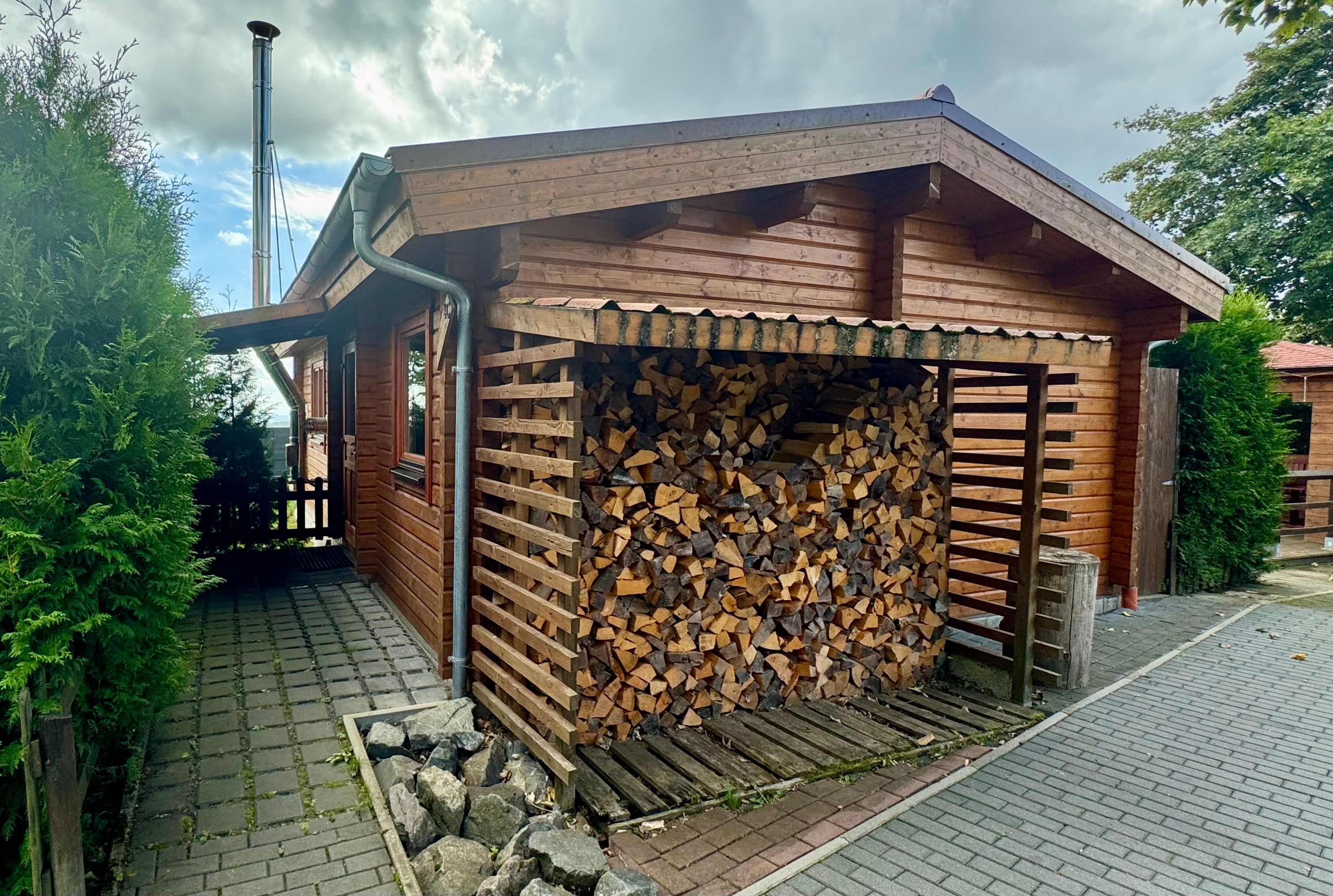 Une cabane en bois avec un bûcher couvert et une cheminée.