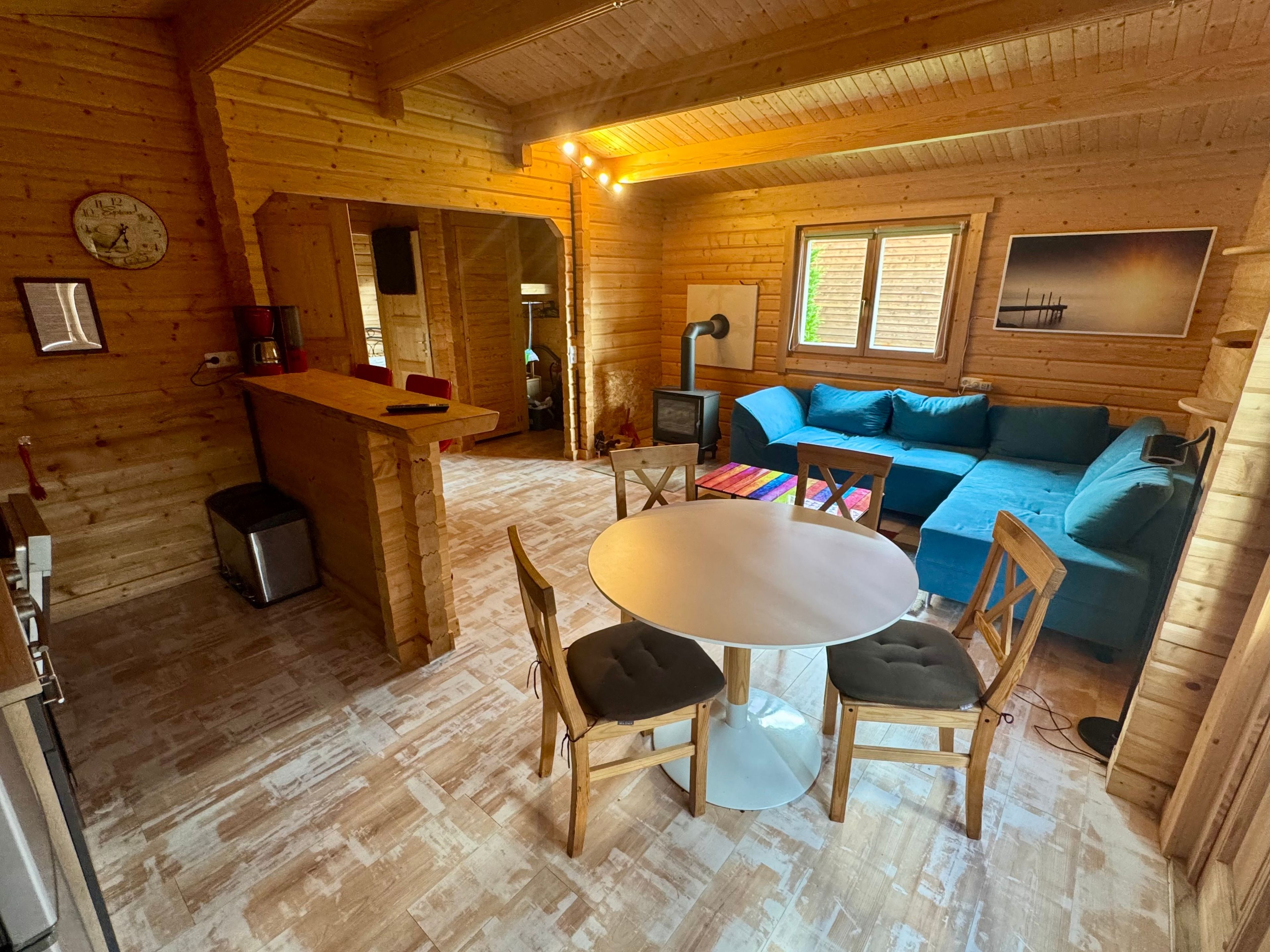 Ein Holzblockhaus-Interieur mit Essbereich, einer Couch und einem Kamin.