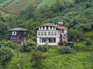 A traditional half-timbered house with a balcony, surrounded by lush greenery.