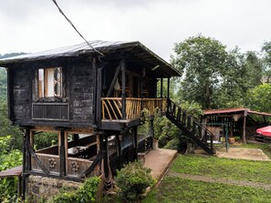 A wooden house with a balcony and a staircase leading to a lower level.