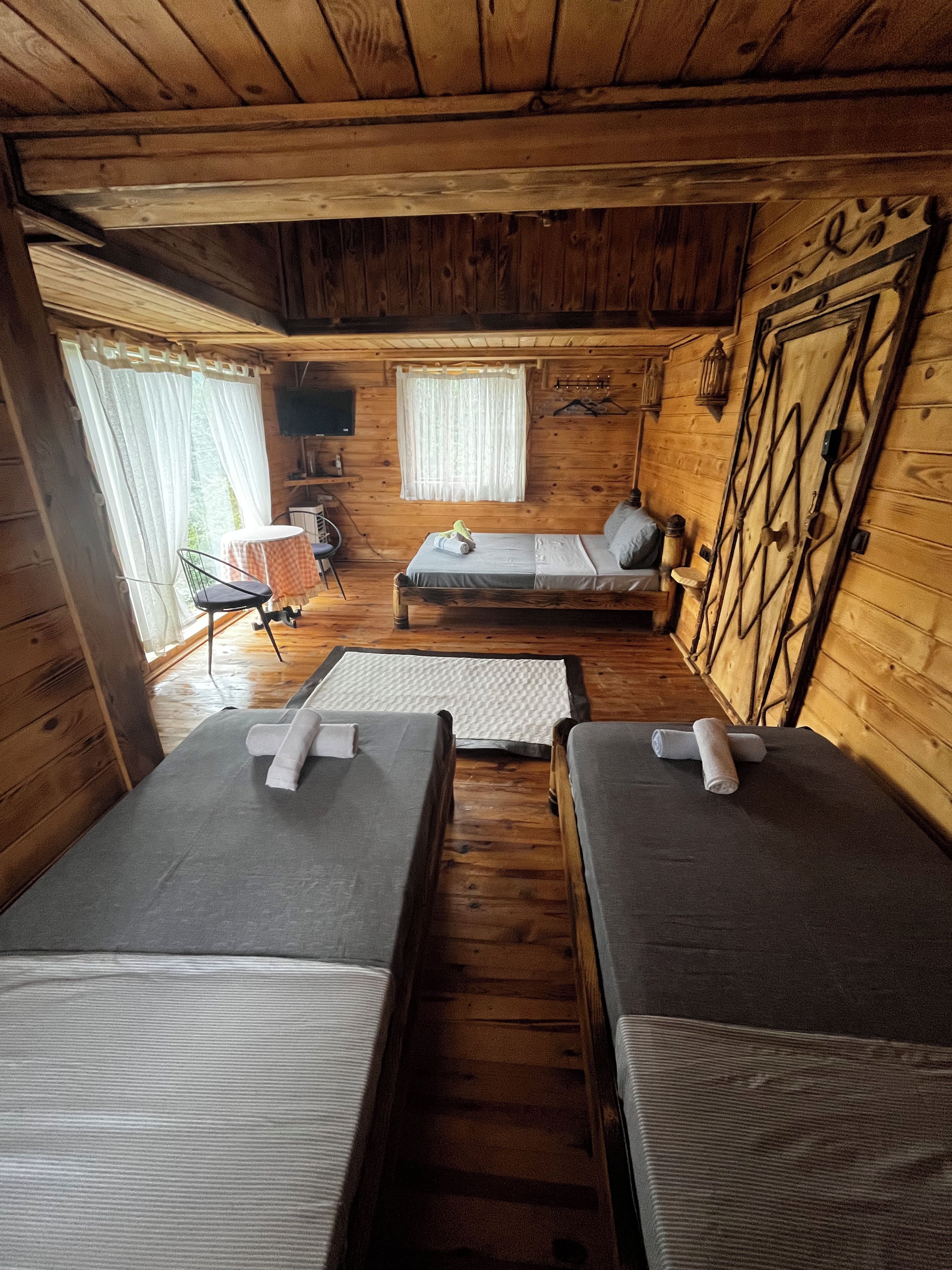 A cabin with two beds, a table, a chair, and a window with curtains.