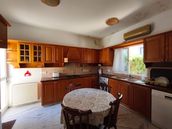 A kitchen with wooden cabinets, a round dining table, and a window providing natural light.