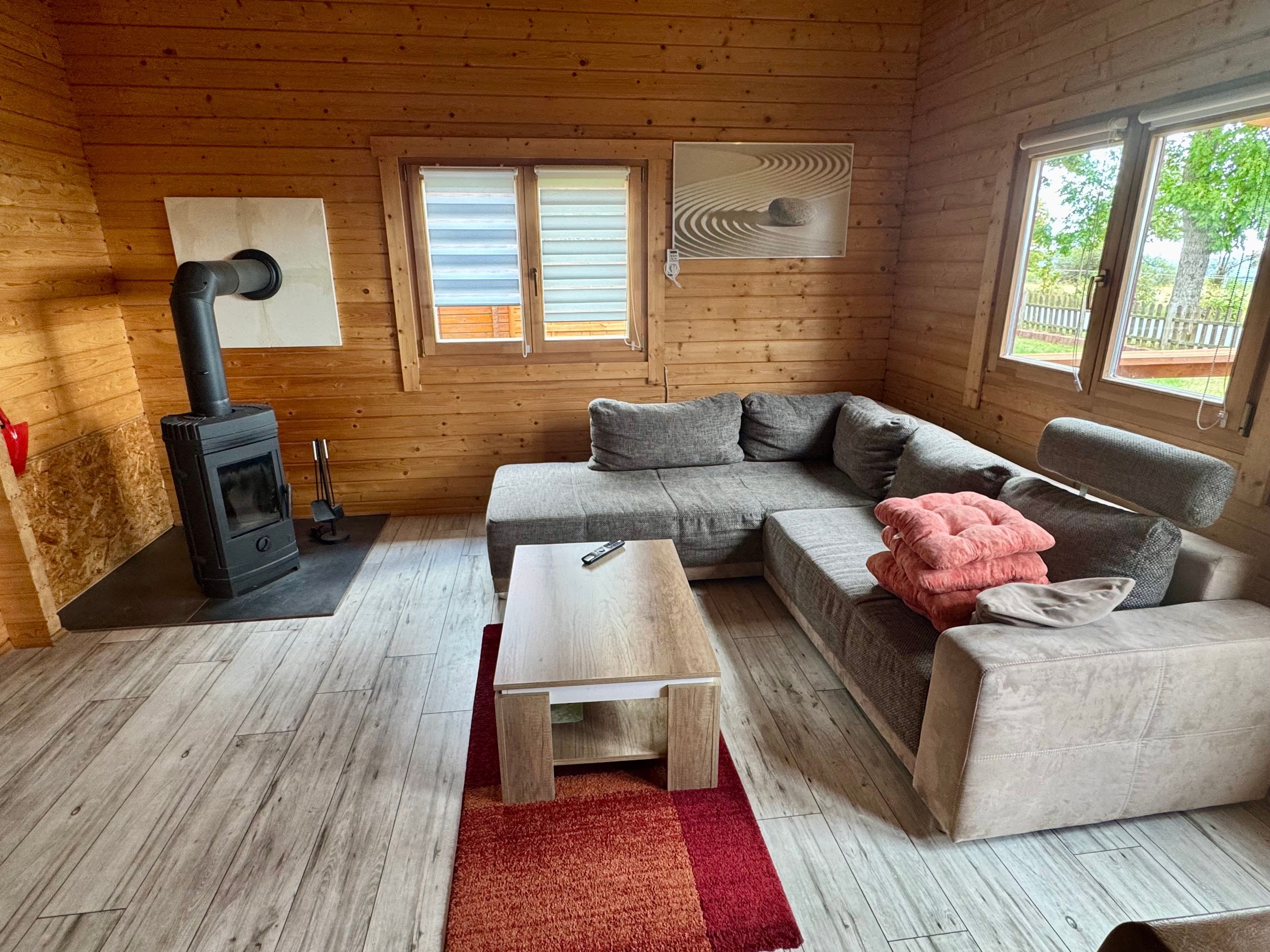 L’intérieur chaleureux d’un chalet, avec un revêtement mural en bois, un canapé, une table et un poêle à bois.